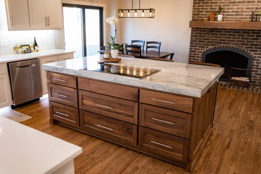 A custom-built wood and marble kitchen island that features an integrated cooktop is the centerpiece of this recent kitchen remodel in Shawnee, KS.