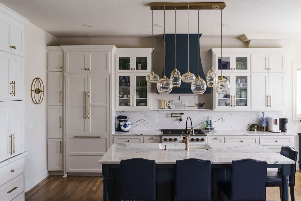 "After" photo of a modern kitchen remodel in Leawood with large white cabinets and hanging pendant lights