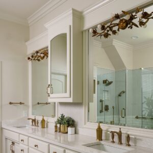 a vanity with gold, floral light fixtures and finishes in a renovated bathroom, completed during an interior remodel in Mission Hills