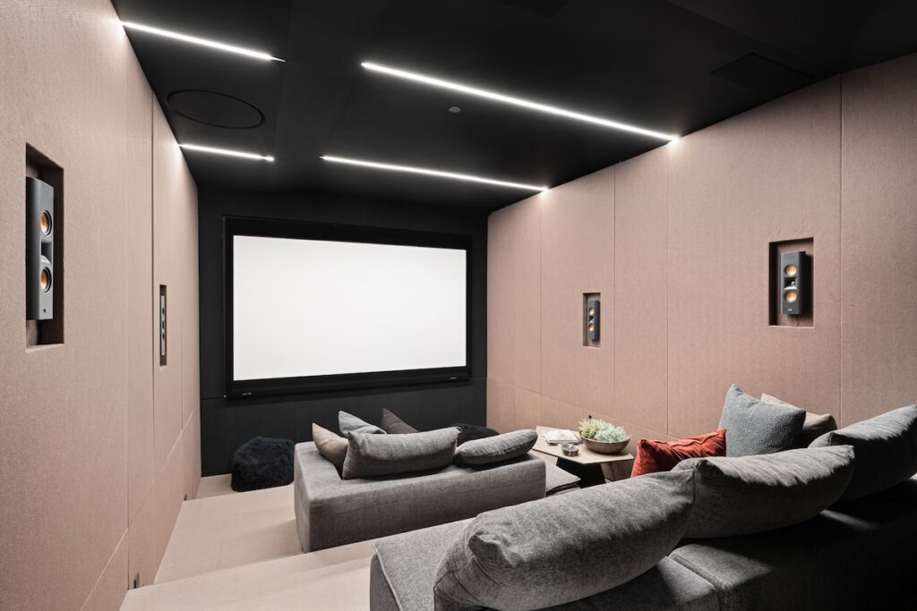 a modern home theatre with a large screen and lounge chairs that Shack Built's basement contractors in Leawood can design and build