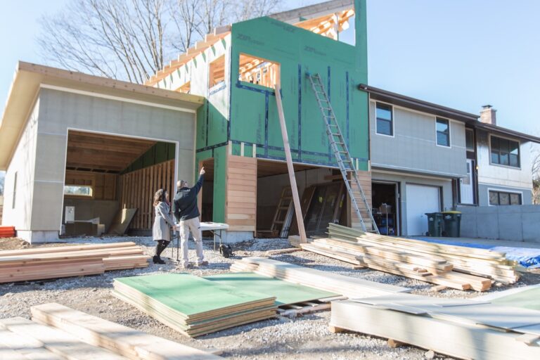 A contractor standing outside an unfinished home to show a client the progress on her home exterior and home interior remodeling in Overland Park